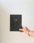 and holding the Jerusalem journal with gold sunrise artwork against a neutral background.