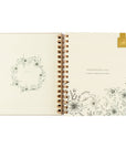 Open planner with floral designs and a belongs to page with magnetic bookmark.