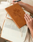Amelia leather-like Christian journal with wildflower design resting on open Bible during quiet time prayer journaling and Scripture study