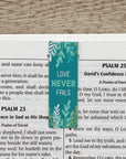 Teal bookmark with 'Love Never Fails' text on a bible background