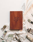 Vienna Christian notebook journal with floral design on warm brown leather-like cover styled in lifestyle setting for prayer journaling, Scripture reflection, and faith-inspired writing