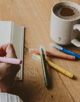 Waxed bible highlighters on wooden desk with cross coffee mug.