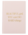 Pink notebook with gold text on a white background