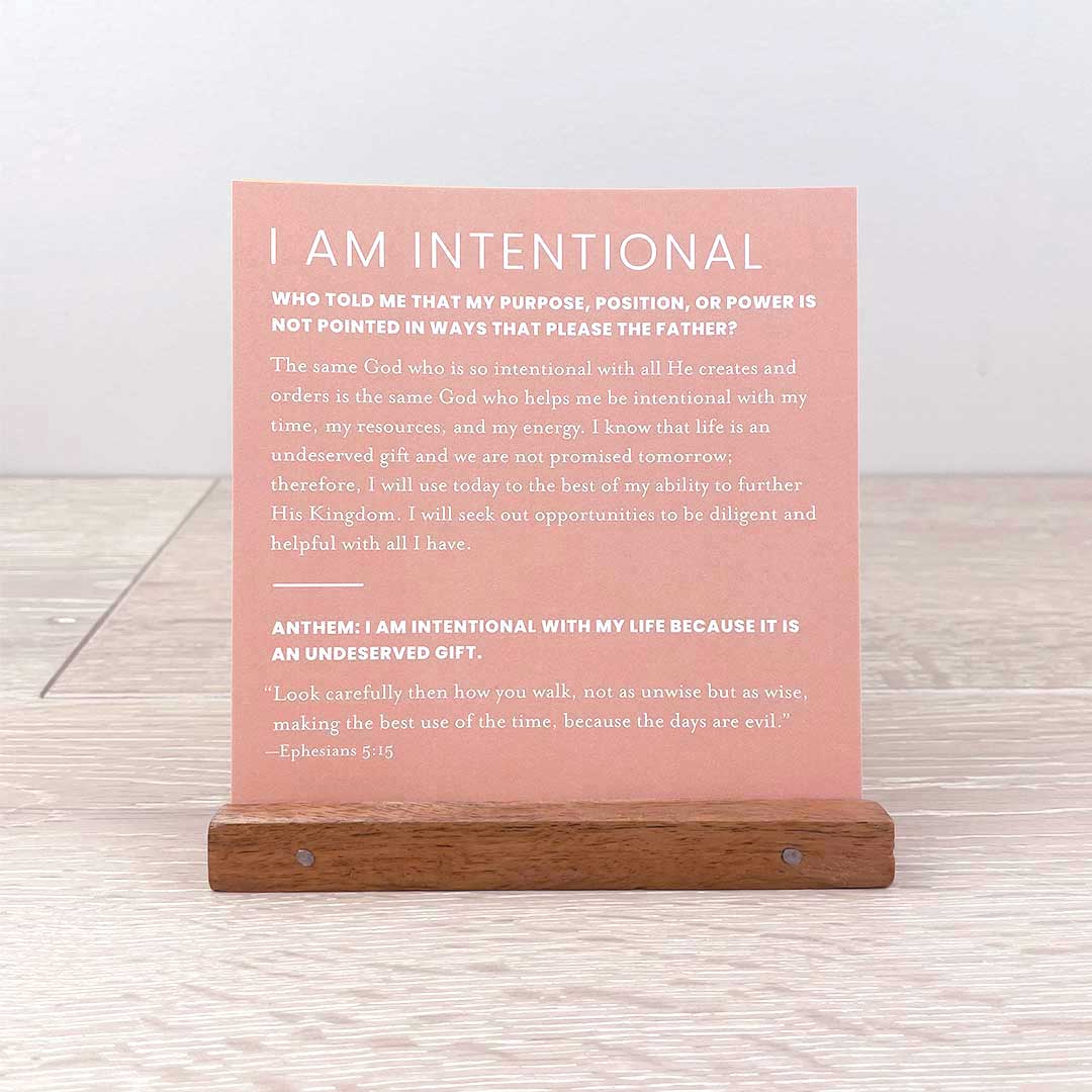 A wooden stand holding a pink inspirational card with text, part of the Worthy Collection.