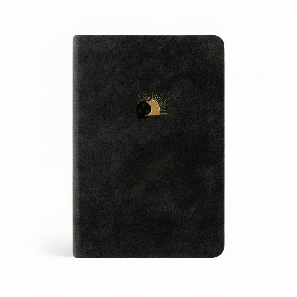 A black leather-like compact Bible with red letter text and a gold foil design on the cover, featuring a stylized sun and moon.