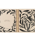 Open notebook with black floral designs on beige pages front and back cover laid flat. Cling to What is Good from Romans is displayed on back cover. 