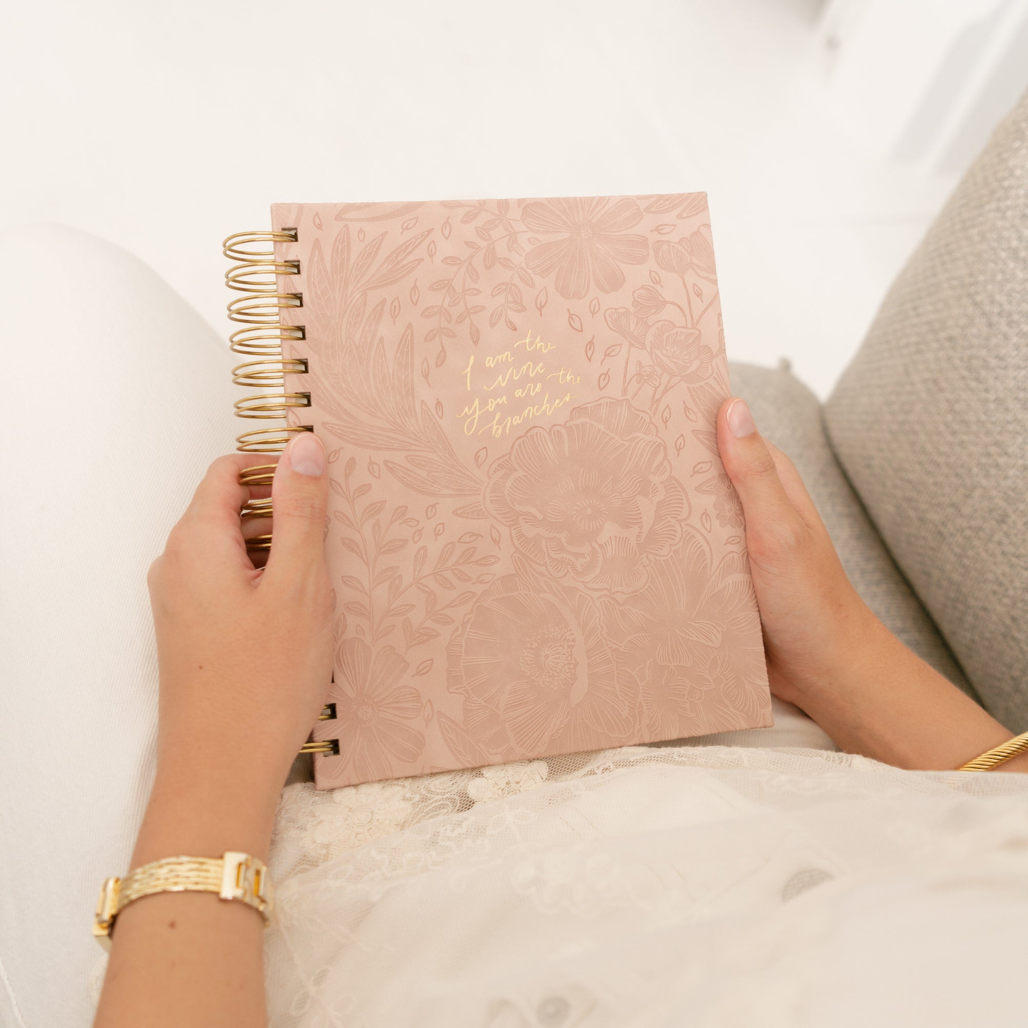 Person holding a pink undated  12-month Christian planner with gold text &quot;I am the vine you are the branches&quot;