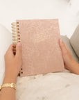 Person holding a pink undated  12-month Christian planner with gold text "I am the vine you are the branches"