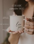 Person holding a Love You ceramic campfire mug. Graphic lists 11 oz capacity, two-sided design, stackability, USA design, and dishwasher and microwave safety.