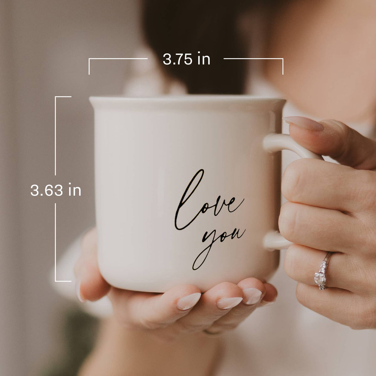 Person holding a cream Love You campfire mug, with dimensions labeled 3.75 inches wide and 3.63 inches tall.