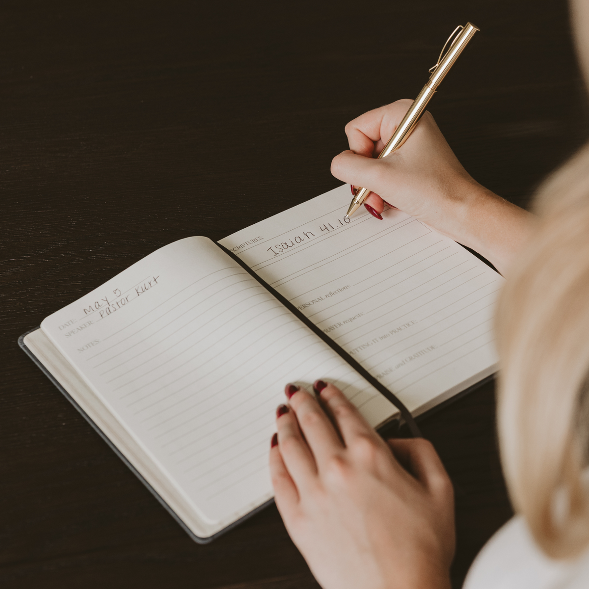 Person writing a Scripture reference in an open Cross Sermon Notes Journal with lined pages and prompts for notes and reflection.