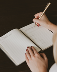 Person writing a Scripture reference in an open Cross Sermon Notes Journal with lined pages and prompts for notes and reflection.