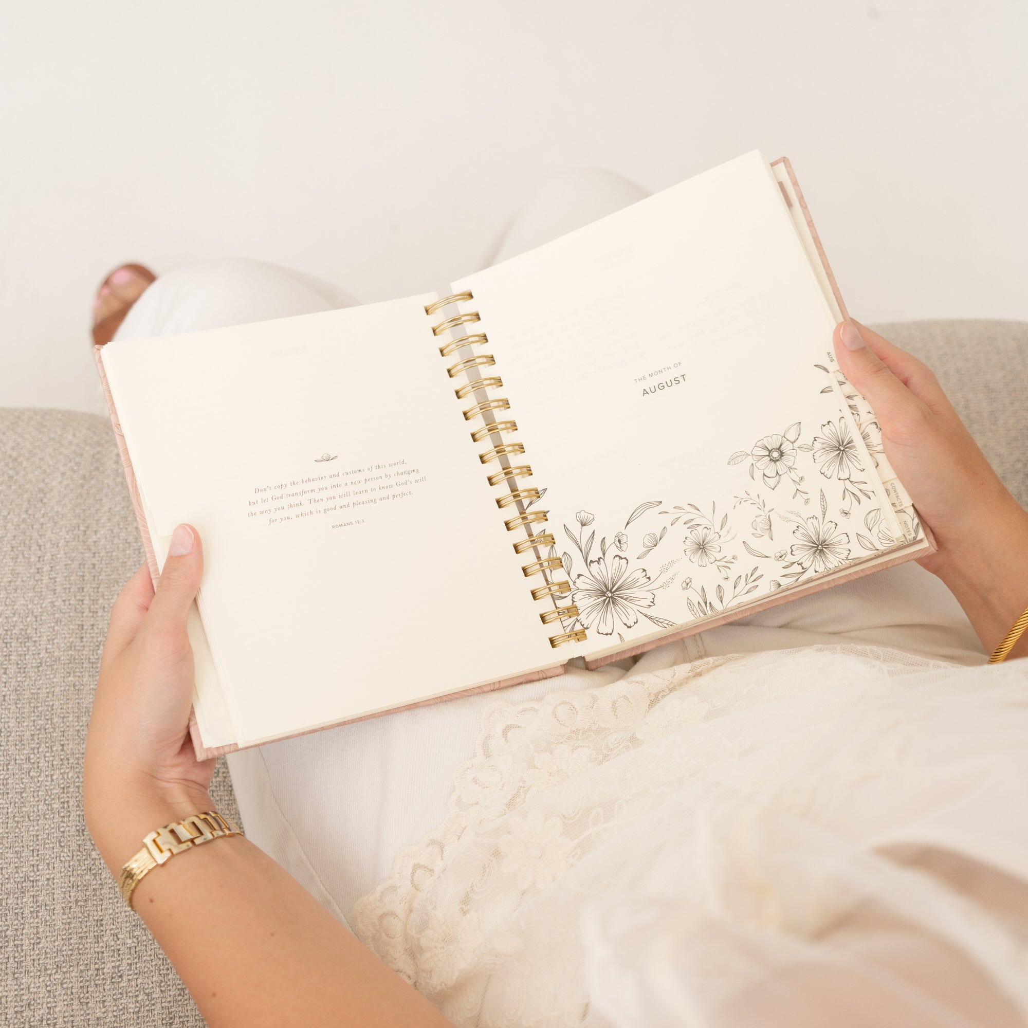 Person holding a spiral-bound planner open to new month and scripture