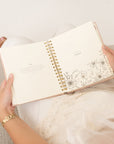 Person holding a spiral-bound planner open to new month and scripture