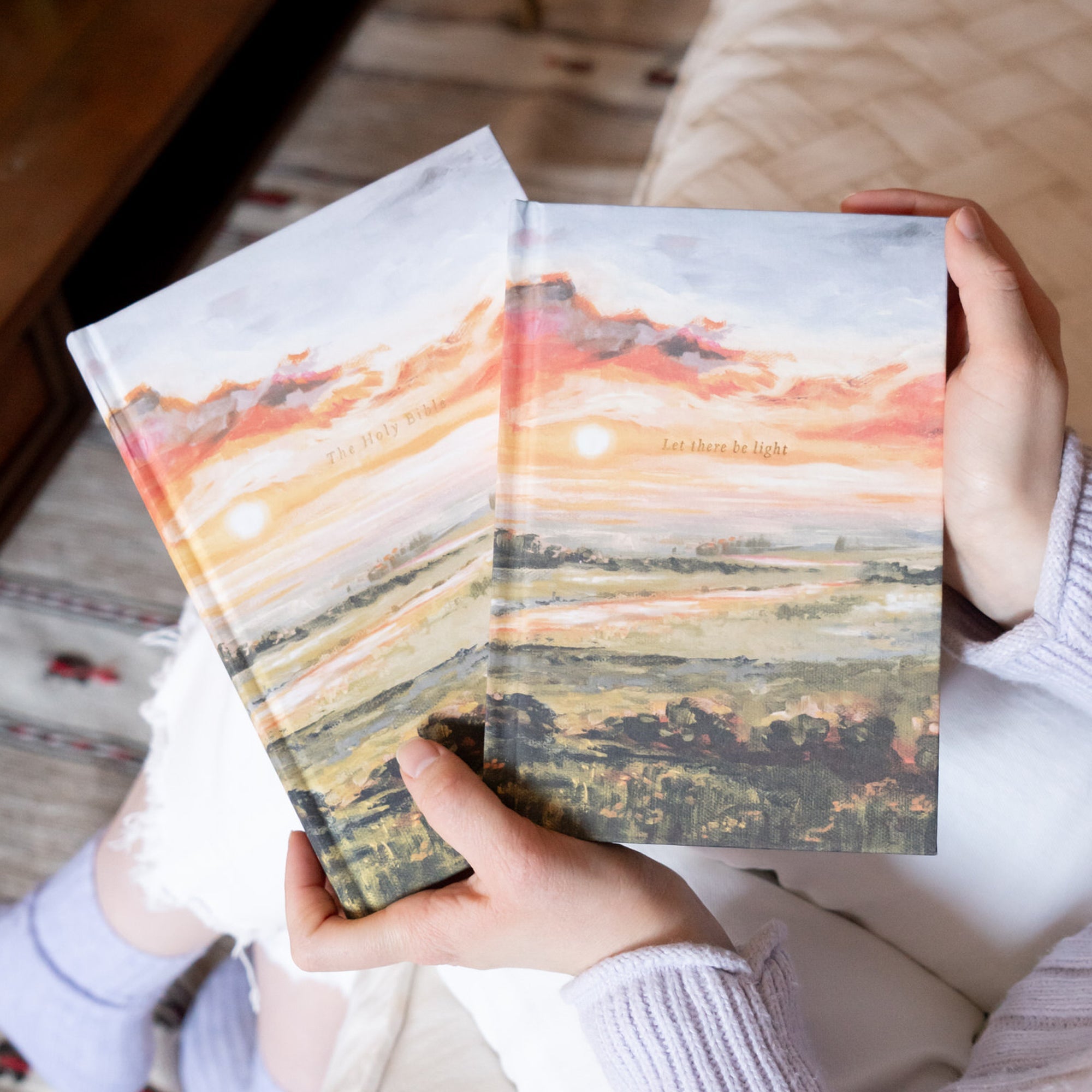 Hands holding Florence Christian notebook showing Let there be light  and the ESV Florence journaling bible in matching sunset cover design in soft natural setting