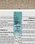 Teal magnetic bookmark with text: "Plans to give you hope and a future" Jer. 29:11" on a bible background in Psam 23 to 25. 