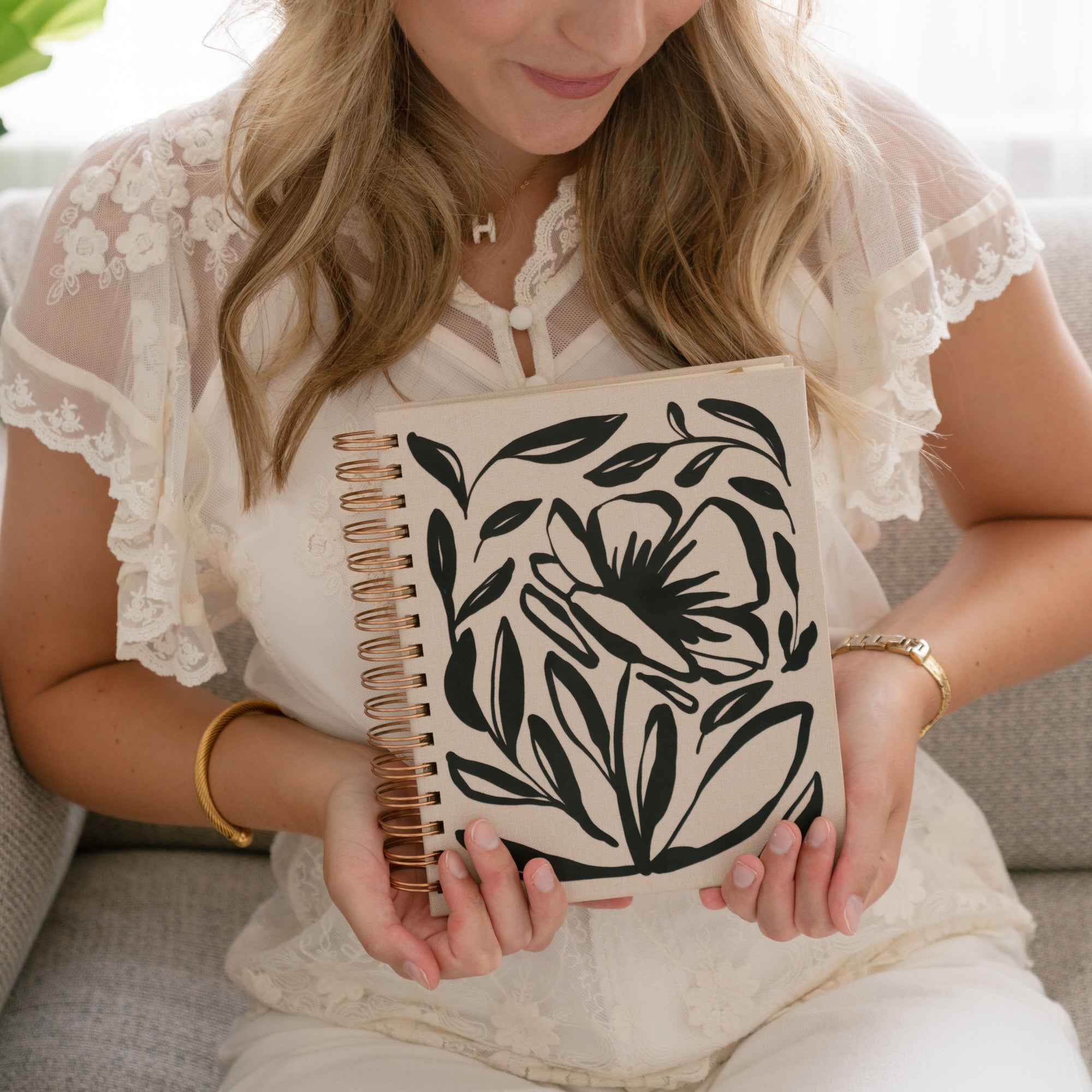 Woman holding a notebook with magnolia floral design front cover of undated Chistian planner