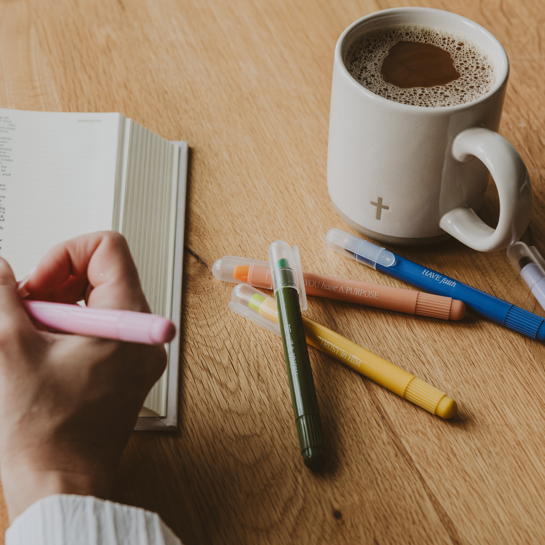 Waxed bible highlighters on wooden desk with cross coffee mug. 
