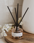 Wildflowers and salt reed diffuser in beige glass jar with black reeds styled on wooden surface with neutral home decor